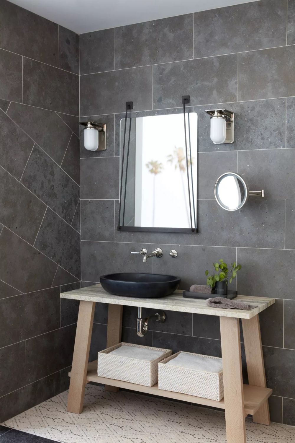 Крупноформатная серая плитка, которой облицованы стены от пола до потолка, наделяет ванную комнату целостным образом.
